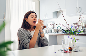 Woman sneezing at table